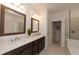 Bright bathroom featuring double vanity, framed mirrors, with bathtub and glass shower at 3195 Bartee Walk, Suwanee, GA 30024