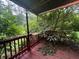 Cozy covered porch with red painted wood, surrounded by lush greenery and mature trees at 5121 Newark Ave, Clarkdale, GA 30111