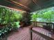 A covered porch with wood plank flooring is surrounded by dense trees and green shrubbery at 5121 Newark Ave, Clarkdale, GA 30111