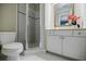 Compact bathroom featuring a glass-enclosed shower, toilet, and a vanity with a decorative mirror and fresh flower at 663 Clifton Ne Rd, Atlanta, GA 30307