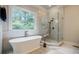 Relaxing bathroom featuring a soaking tub, walk-in shower, and a large window with backyard views at 663 Clifton Ne Rd, Atlanta, GA 30307