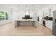 Spacious kitchen features an island with waterfall countertop, stainless steel appliances and wine cooler at 1387 Mineral Springs Rd, Hoschton, GA 30548