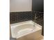 Bathroom featuring a soaking tub with black tiled walls and gold fixtures at 870 Mayson Turner Nw Rd # 1102, Atlanta, GA 30314