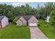 Aerial view of a brick house with lush green lawn, long driveway, and mature trees in a quiet neighborhood at 605 Pebble Blvd, Covington, GA 30016