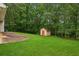 Large, grassy backyard featuring a storage shed and a tree line at 605 Pebble Blvd, Covington, GA 30016