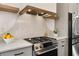 Close up of the kitchen features stainless steel range and hood, wooden shelves, and marble backsplash at 2347 Hosea L Williams Ne Dr # 11, Atlanta, GA 30317