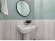 Stylish powder room featuring a white pedestal sink, round mirror, and light blue walls at 2347 Hosea L Williams Ne Dr # 11, Atlanta, GA 30317