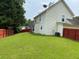 Large, grassy backyard with a red fence, with the side and rear of the house in view at 4424 High Gate Nw Dr, Acworth, GA 30101