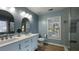Well-lit bathroom with dual sink vanity, a stylish wall mirror, and a modern glass shower at 4424 High Gate Nw Dr, Acworth, GA 30101