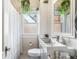 Cozy bathroom featuring a modern sink, toilet, shower with curtain, and a window with hanging plants at 451 S Columbia Dr, Decatur, GA 30030