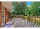 View of the backyard from a wooden deck, with brick house, wooden railing and mature trees at 57 Jonathan Rd, Riverdale, GA 30274
