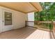 Lovely covered back porch with wooden railings and a view of the greenery around the property at 5365 Winding Ln, Suwanee, GA 30024