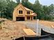 New construction home exterior shows exposed framing on a large lot with gravel and dirt at 731 Crest Line Trl, Powder Springs, GA 30127