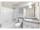 Bright bathroom featuring a white-tiled shower and tub, vanity with granite countertop, and patterned flooring at 2135 Knighton Dr, Atlanta, GA 30349