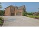 Spacious three-car garage with a long driveway, surrounded by well-maintained landscaping and lush greenery at 2450 Weber Heights Way, Buford, GA 30519
