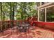 Exterior red deck with metal table and chairs, surrounded by a lush green forest and connecting to a glass sunroom at 912 Chipley Ct, Marietta, GA 30062