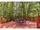 Exterior red deck with metal table and chairs, surrounded by a lush green forest at 912 Chipley Ct, Marietta, GA 30062