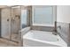 Bathroom featuring a soaking tub, glass-enclosed shower, and a bright window with blinds at 90 Citrine Way, Acworth, GA 30101