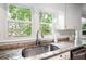 Close-up view of a kitchen sink under a window with granite countertops and white cabinets at 4497 Windsor Oaks Dr, Marietta, GA 30066