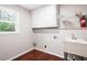 Functional laundry room featuring a utility sink, storage cabinets, and a window for natural light at 4497 Windsor Oaks Dr, Marietta, GA 30066