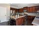 Kitchen features stainless appliances, dark wood cabinets and flooring, and an island with bar seating at 2555 Blackstock Dr, Cumming, GA 30041