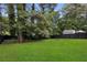 Expansive backyard with a lush lawn, mature trees, a wood fence, and a storage shed at 6322 Phillips Creek Dr, Lithonia, GA 30058