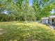 Large backyard with mature trees, lush lawn, and a wooden deck at 30 Court S, Ellenwood, GA 30294