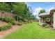 Expansive backyard with manicured lawn, vibrant flowerbeds, and a charming covered patio, creating a serene outdoor space at 1650 Walking Horse Trl, Cumming, GA 30041