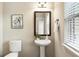Compact half bathroom featuring a pedestal sink, toilet, and decorative mirror at 1650 Walking Horse Trl, Cumming, GA 30041