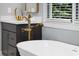 Charming bathroom with a soaking tub, a vintage-style faucet, gray cabinets, and natural light at 1461 Bubbling Creek Ne Rd, Brookhaven, GA 30319
