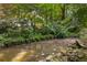 Scenic view of a creek flowing through a lush, green landscape with natural rock formations and stone retaining wall at 1461 Bubbling Creek Ne Rd, Brookhaven, GA 30319