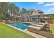 Expansive backyard with a sparkling pool, a covered patio, lush lawn, and mature trees, perfect for entertaining at 33 Vinery Ct, Sharpsburg, GA 30277