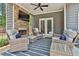 Inviting covered patio with stone fireplace, ceiling fan, and cozy wicker furniture for relaxing or entertaining at 33 Vinery Ct, Sharpsburg, GA 30277