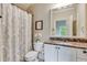 Bathroom with marble countertop, decorative mirror, and shower with curtain at 5623 Brendlynn Dr, Suwanee, GA 30024