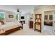 A spacious bedroom with neutral walls features a ceiling fan, windows overlooking the green landscape, and a doorway to another room at 5623 Brendlynn Dr, Suwanee, GA 30024