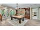 Well-lit game room featuring a billiard table, stone fireplace, and built-in bookshelves at 5623 Brendlynn Dr, Suwanee, GA 30024