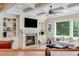 Cozy living room with a fireplace, built-in shelving, and a bright window with a green backyard view at 5623 Brendlynn Dr, Suwanee, GA 30024