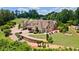 A large home with a stone retaining wall, patio with red umbrellas, and lush landscaping at 2220 Peachtree Rd, Cumming, GA 30041