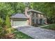 Two-story brick home with a two-car garage and a concrete driveway nestled among trees at 2982 Huntshire Pl, Atlanta, GA 30340