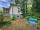 Back exterior view of a modest home with overgrown landscaping and debris in the backyard at 53 Elm St, Hampton, GA 30228