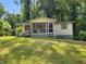 Modest single-story home with screened-in porch and a sloped walkway, set against a backdrop of lush greenery at 53 Elm St, Hampton, GA 30228