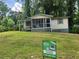 A cozy home with a 'For Sale' sign on the lawn, surrounded by lush trees and bushes at 53 Elm St, Hampton, GA 30228
