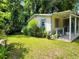 Quaint single story house on a large lawn with overgrown landscaping and a partially covered porch on its side at 53 Elm St, Hampton, GA 30228
