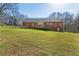 Back exterior view of a brick house with a deck, situated on a large, grassy lot at 5826 Little Mountain Dr, Ellenwood, GA 30294
