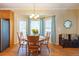 Sunlit dining area features a round wood table and chairs by bay windows with elegant light fixture and wood floors at 5826 Little Mountain Dr, Ellenwood, GA 30294