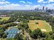 An aerial view showcasing a park, athletic fields, tennis courts, pools, and the city skyline at 893 Piedmont Ne Ave # 3, Atlanta, GA 30309