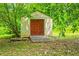 An exterior view of the shed with a neutral exterior and a contrasting reddish-brown door at 3449 Parkview Dr, Atlanta, GA 30337