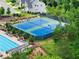 Aerial view of blue and green tennis courts with a pool and lounge chairs in a residential community at 4105 Woodwind Dr, Cumming, GA 30028