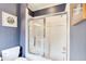This bathroom is equipped with a glass-door shower and a toilet set against blue striped wallpaper and framed art at 115 Cross Roads Ct, Atlanta, GA 30327