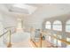 Upstairs hallway with glass railings overlooking great room and large arched windows at 115 Cross Roads Ct, Atlanta, GA 30327